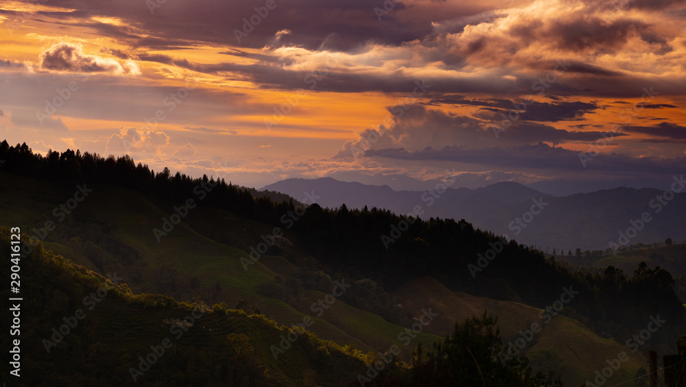 Naklejka premium atardecer con cielo de tonos azules y naranjas entre montañas