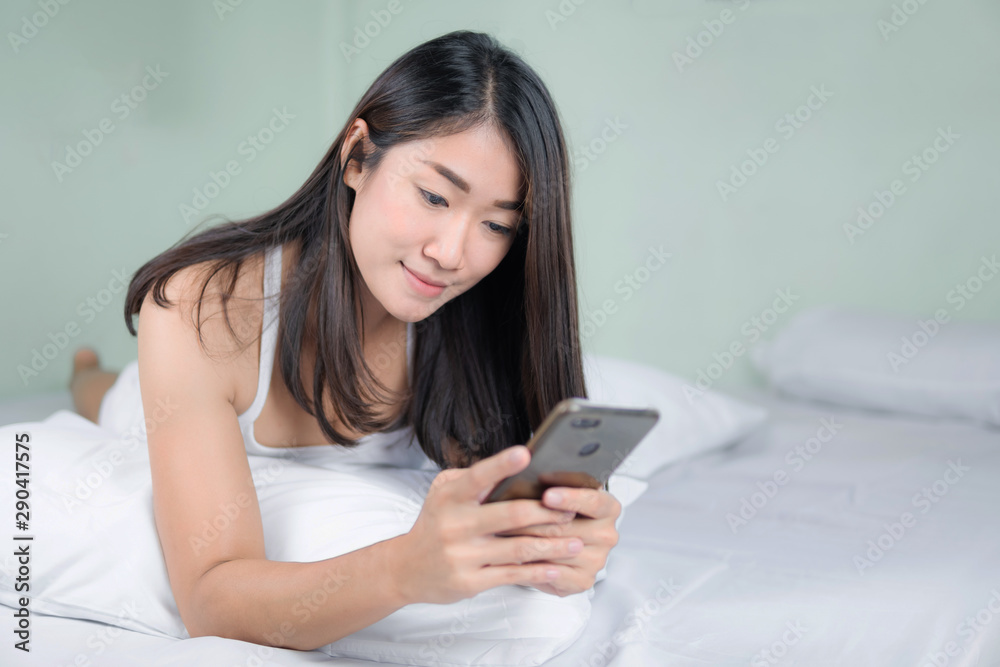 Cute asian woman use of mobile phone in bedroom and smile. Cute asian woman use of mobile phone in bedroom and smile.