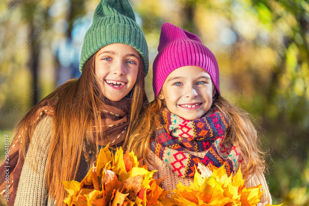 Two cute smiling 8 years old girls posing together in a park on a sunny autumn day. Friendship concept. Two cute smiling 8 years old girls posing together in a park on a sunny autumn day. Friendship concept.