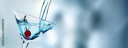 Canvas Print Pouring Martini cocktail in glass  on blurred background