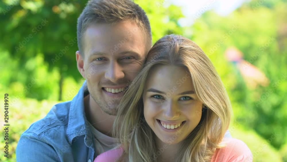 Cheerful young man embracing beautiful female, happy couple smiling on camera Cheerful young man embracing beautiful female, happy couple smiling on camera