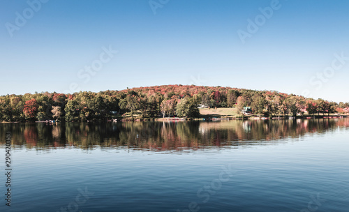 Fall colours of Muskoka Ontario. With Setting sun over the lake and water reflecting the trees as the colors change.