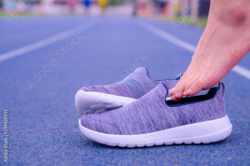 A man is taking on grey sports shoes on the running track. Sport and exercise concept.