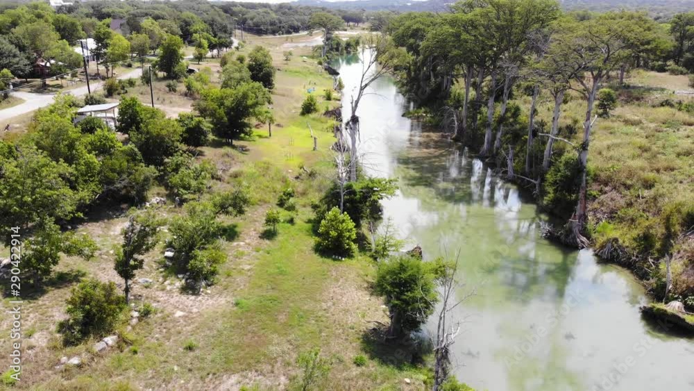 Pulling away, flying back above river towards the edge of the riverbank and then descending to land - Aerial footage of the Blanco river in Wimberly, TX Pulling away, flying back above river towards the edge of the riverbank and then descending to land - Aerial footage of the Blanco river in Wimberly, TX
