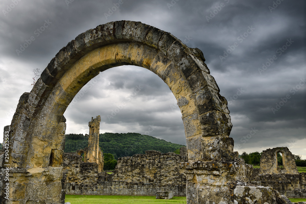 Arch ruin on wall surrounding the site of Byland Abbey in North York Moors National Park England under dark clouds