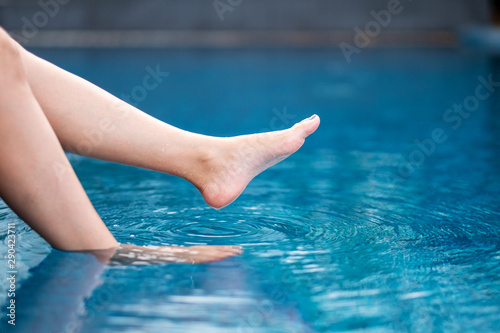 Closeup image of legs and bare feet soaking water in the pool