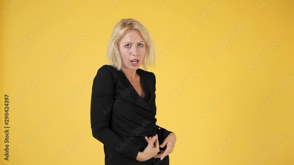 Beautiful girl with white hair in a black dress on a yellow background posing and stroking herself Beautiful girl with white hair in a black dress on a yellow background posing and stroking herself