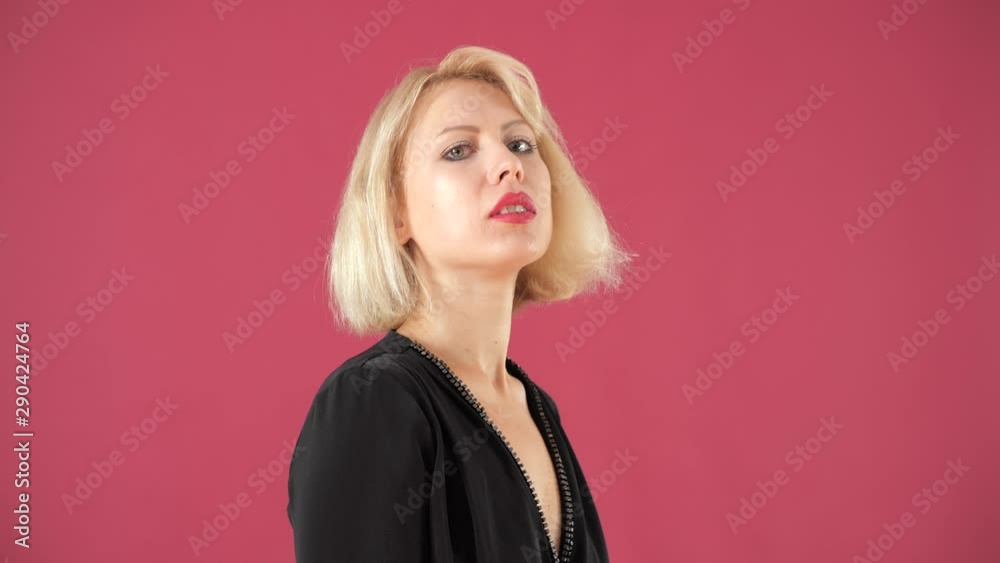 Beautiful blonde girl in a black jumpsuit moves sexually on a pink background. Beautiful blonde girl in a black jumpsuit moves sexually on a pink background.