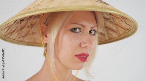 Close-up. Beautiful European girl on a white background in a straw conical hat (nonla) posing for the camera. photo