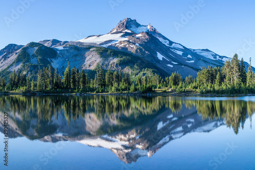 Volcanic mountain in morning light reflected in calm waters of lake.	