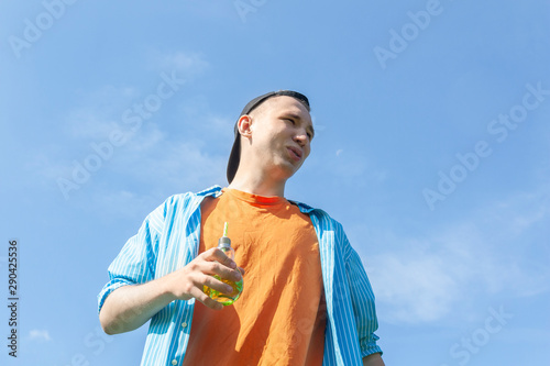 A guy with a beverage in his hand against a blue sky