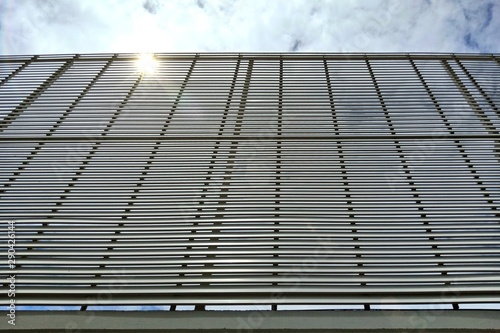 Angle view of steel fence against the sky and sun rays