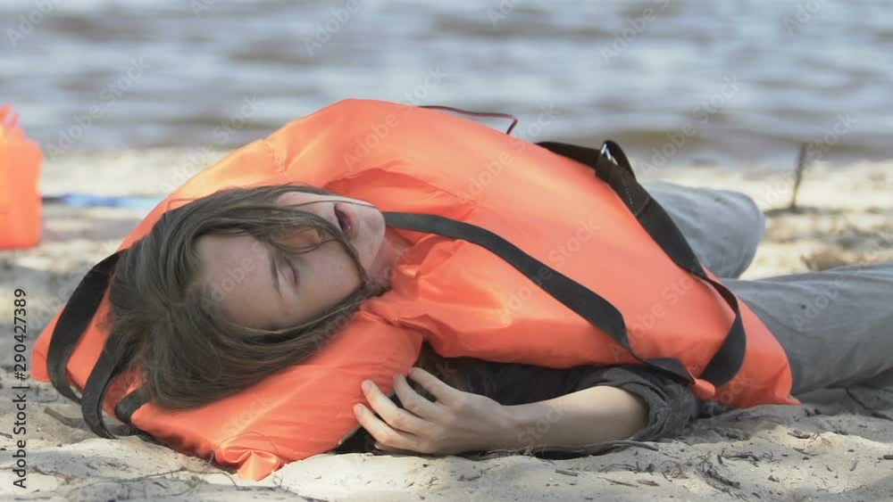Survived female taking off life vest and coughing on sea coast after plane crash