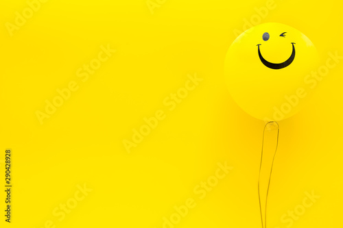 Happiness emotion. Yellow balloon with smile on yellow background top view copy space