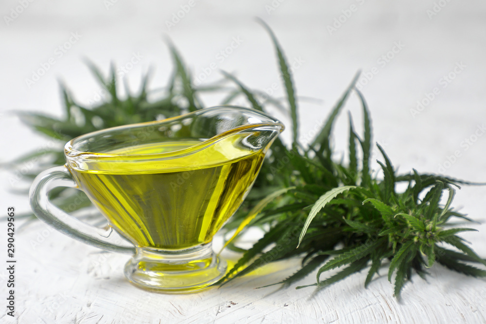 hemp oil. branch of green cannabis . glass vessel with oil . on white textured background. close up. hemp oil. branch of green cannabis . glass vessel with oil . on white textured background. close up.