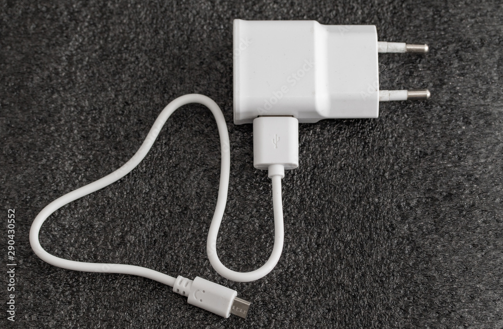 White charger for smartphones on a dark background. White charger for smartphones on a dark background.