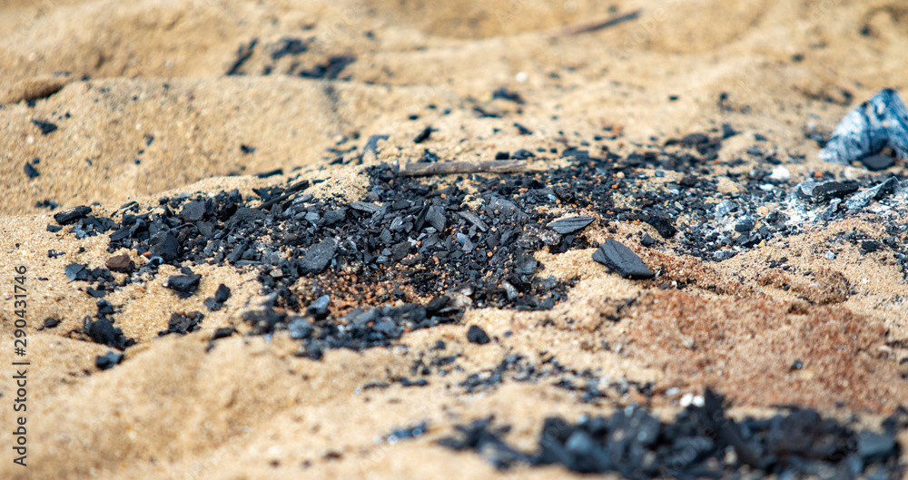 Black coals after a fire on a sandy shore. Black coals after a fire on a sandy shore.