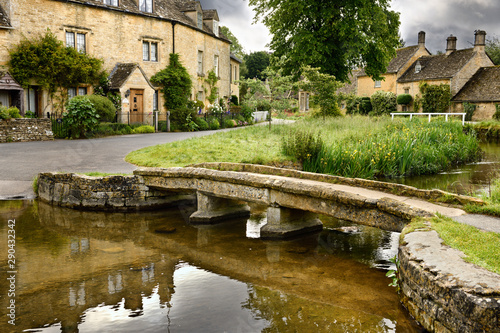 Yellow Cotswold limestone footbridge over the River Eye in Lower Slaughter village in Cheltenham England