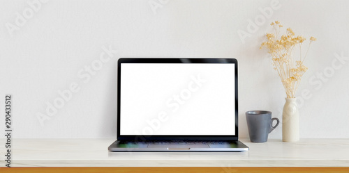Open blank screen laptop computer on white wooden table in white minimal workplace