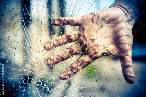 The child presses his hand to the glass. The glass is cracked.