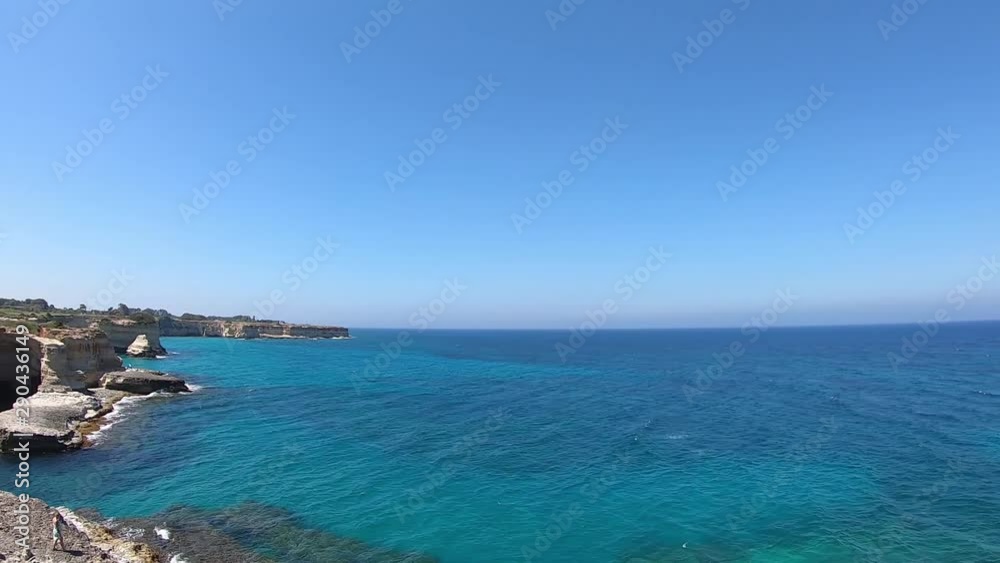 Pan shot of blue sea next to rocks in Salento, Puglia, Italy Pan shot of blue sea next to rocks in Salento, Puglia, Italy