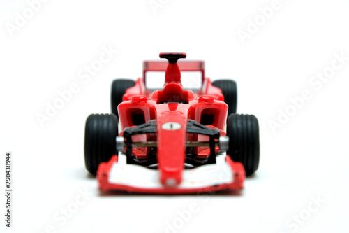 Red toy motor racing car, a model championship high powered motorsport auto racing car for children's fun and play, front closeup view, isolated on white background.
