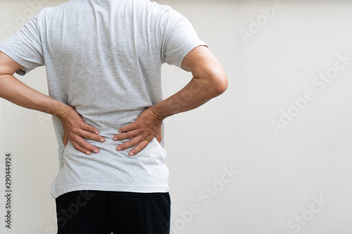 Young man holding his back in pain. Medical concept photo