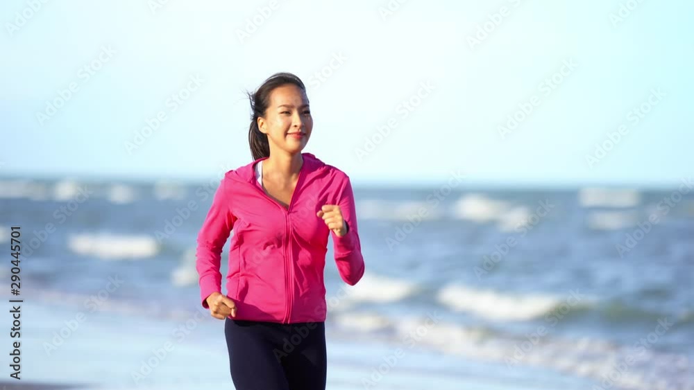 Happy Smiling Asian Female Jogging On Sandy Beach By The Sea on Sunny Morning Happy Smiling Asian Female Jogging On Sandy Beach By The Sea on Sunny Morning