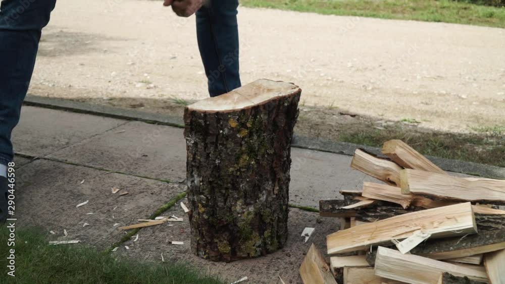 Young man is chopping wood in smaller pieces. Preparing for the for the fire place. Close up shot.