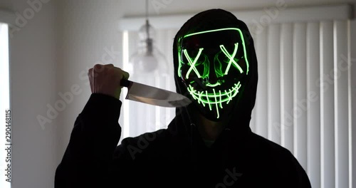 A scary slasher serial killer in a horror halloween mask pulling a knife on his murder victim. photo