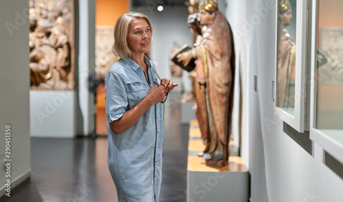 Konstfotografi Mature woman visitor in the historical museum looking at pictures