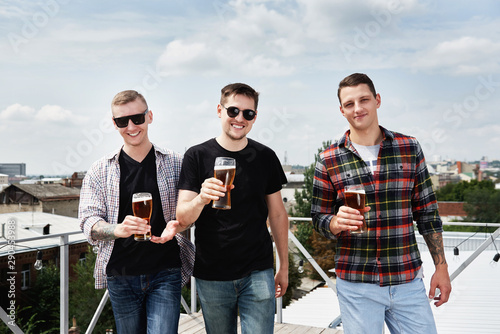 Happy smiling male friends drinking beer at bar or pub on roof, copy space. Friendship and celebration concept