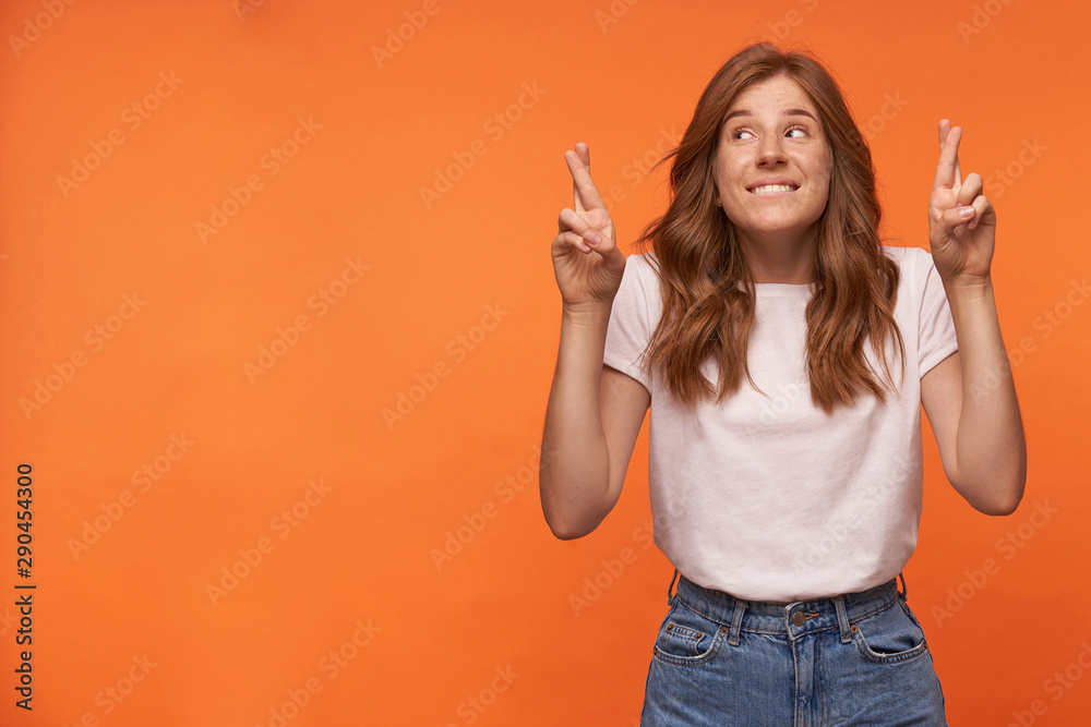 Studio photo of charming young redhead woman with hairstyle waring casual clothes, keeping her fingers crossed for good luck, hoping for better - obrazy, fototapety, plakaty 