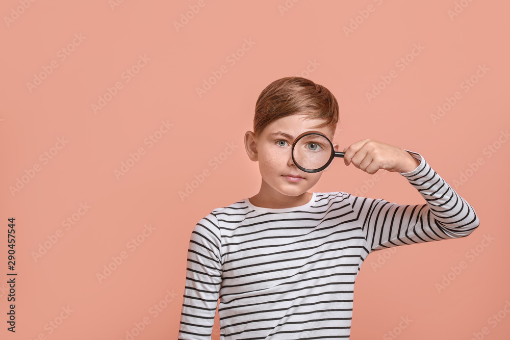 Little boy with magnifying glass on color background