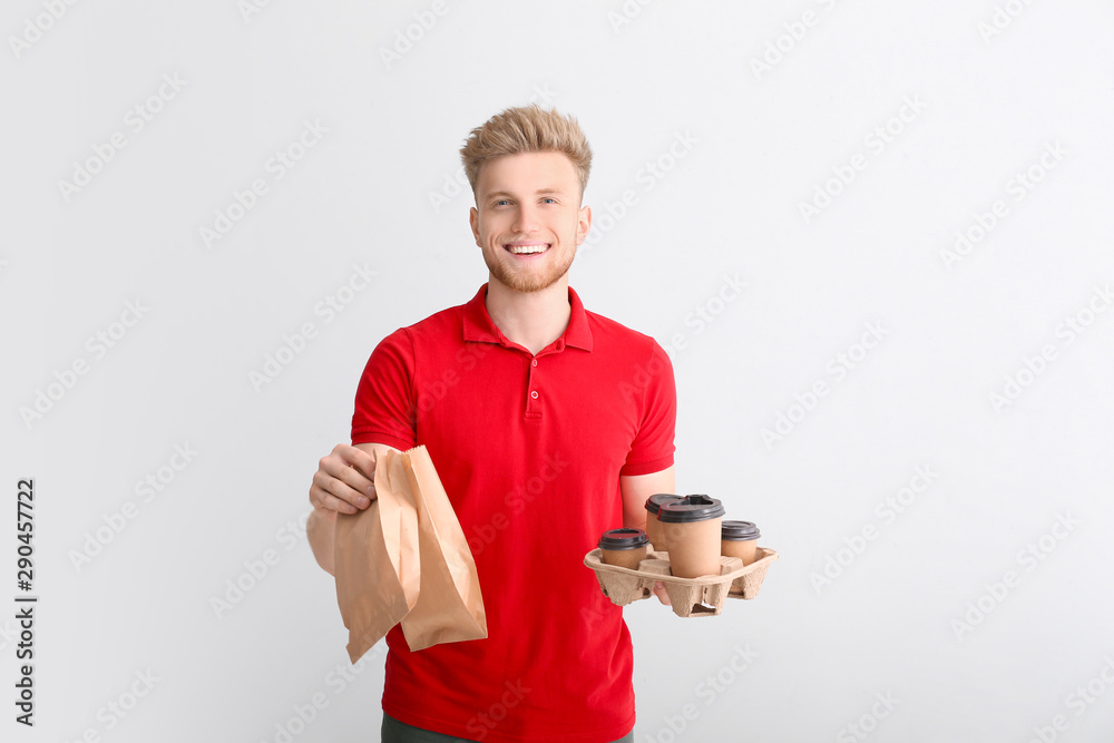 Handsome worker of food delivery service on light background Handsome worker of food delivery service on light background