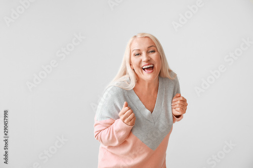 Happy mature woman on grey ...
