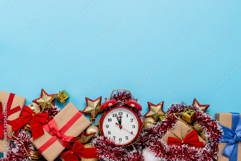 Red alarm clock, Christmas decorations, gifts on a blue background. Merry Christmas and happy new year concept. Copy Space. Flat lay, top view