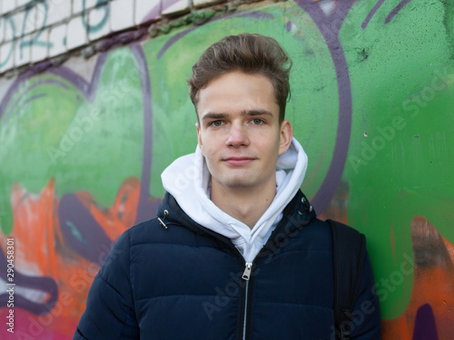 cute smiling teenager against the background of a wall on the street