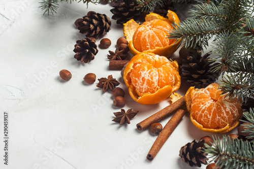 Tangerines without peel, Christmas tree branches, spices, cinnamon, cones on a white stone background. Concept of Christmas, New Year, Mulled Wine.