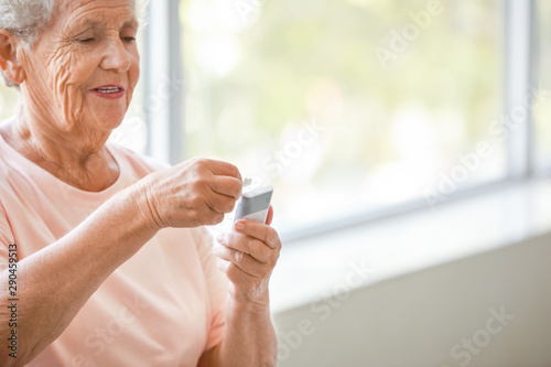 Diabetic woman checking blood sugar level at home photo