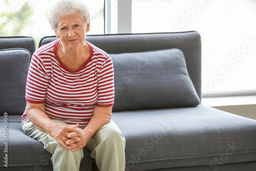 Senior woman suffering from pain in knee at home