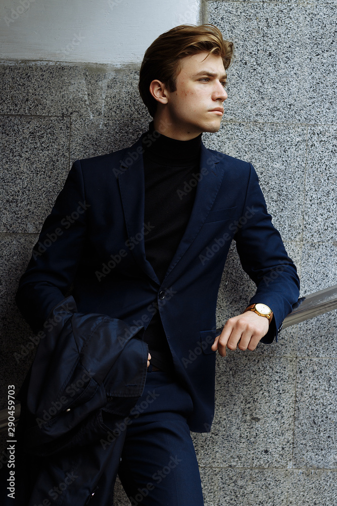 portrait of an attractive young man in a blue suit in the city