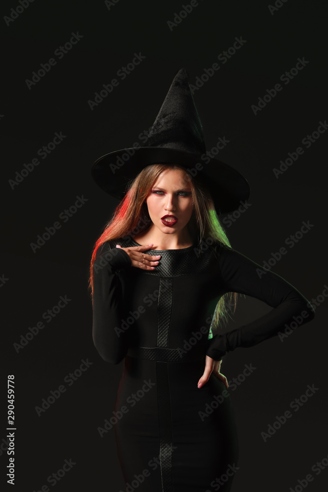 Beautiful woman dressed as witch for Halloween on dark background Beautiful woman dressed as witch for Halloween on dark background