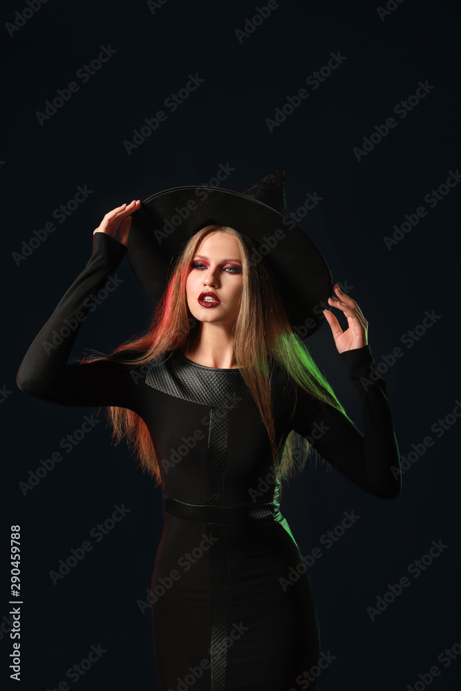 Beautiful woman dressed as witch for Halloween on dark background Beautiful woman dressed as witch for Halloween on dark background