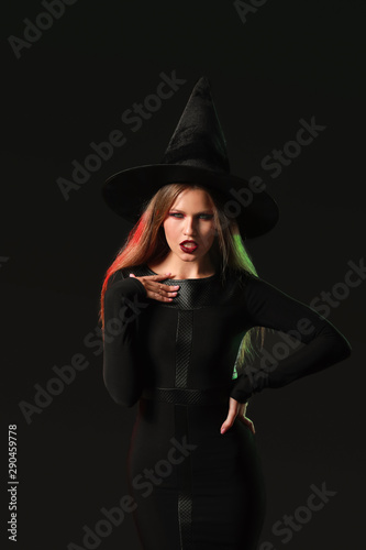 Beautiful woman dressed as witch for Halloween on dark background