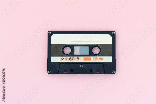 Old audio tape cassette on a pink background. Top view, old technology concept