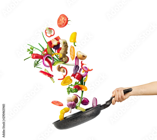 Cooking concept. Vegetables are flying out of the pan isolated on white background. Healthy food.