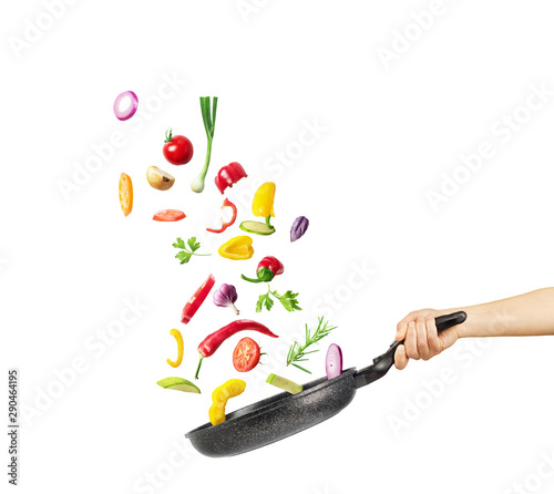 Cooking concept. Vegetables are flying out of the pan isolated on white background. Healthy food. photo