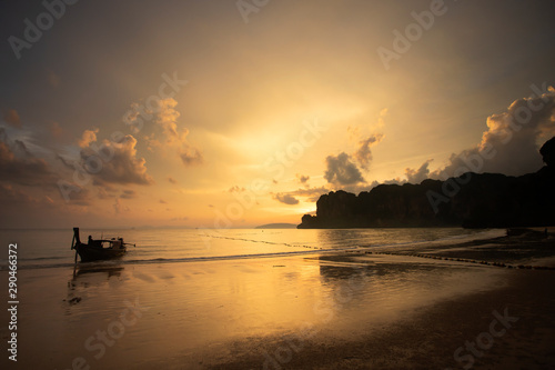 Amazing sunset with longtail boats silhouette at Railay beach, Thailand.