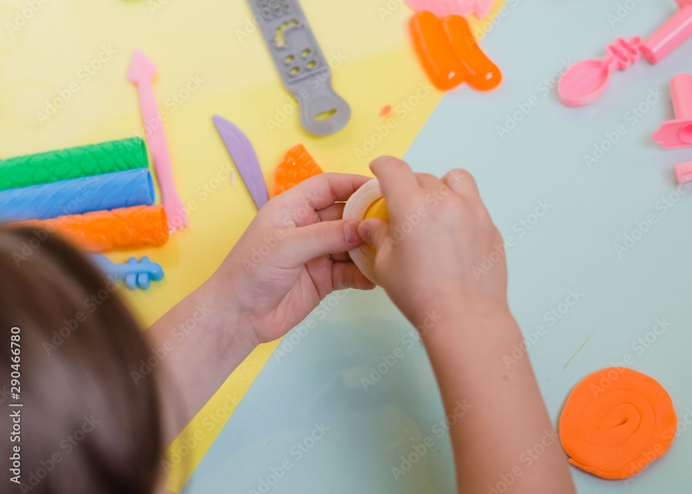 Child's hands with colorful clay. Child playing and creating vagetables from play dough. Girl molding modeling clay. Homemade clay. Child's hands with colorful clay. Child playing and creating vagetables from play dough. Girl molding modeling clay. Homemade clay.